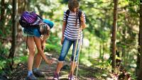 Mother applying insect repellent to daughter's leg during a hike
